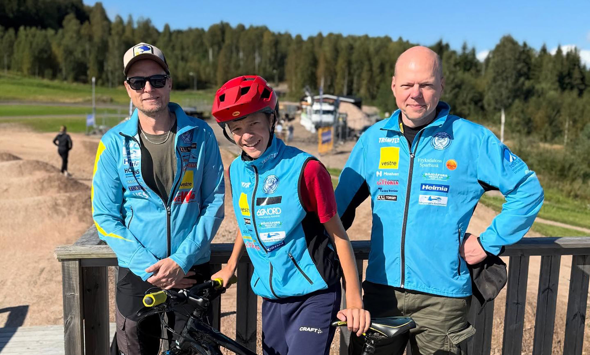 Tre män och en cykel utomhus vid Valberget, Torsby.