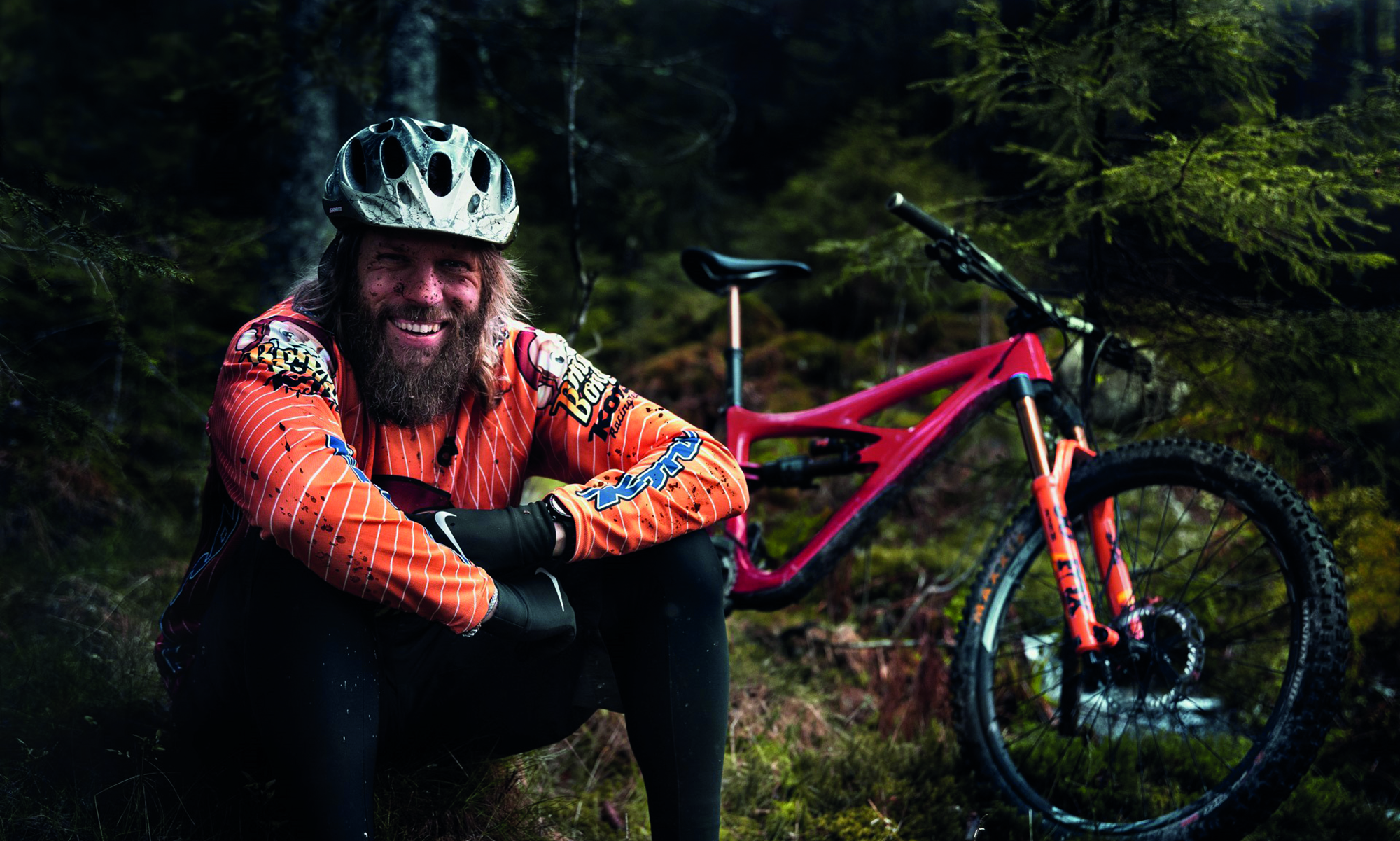 En man sitter i skogen bredvid en cykel